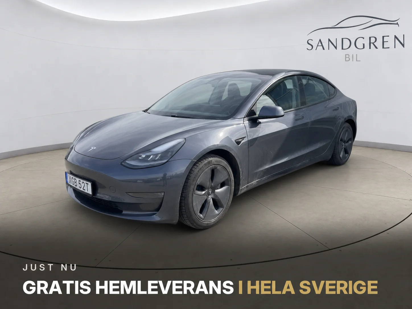 Samma Tesla i en ren studio, med handlarens logga på väggen och ett kampanjbudskap